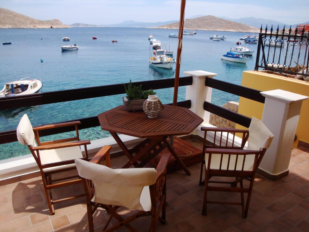 una mesa y sillas en un balcón con vistas al agua en Halkis Muses, en Halki