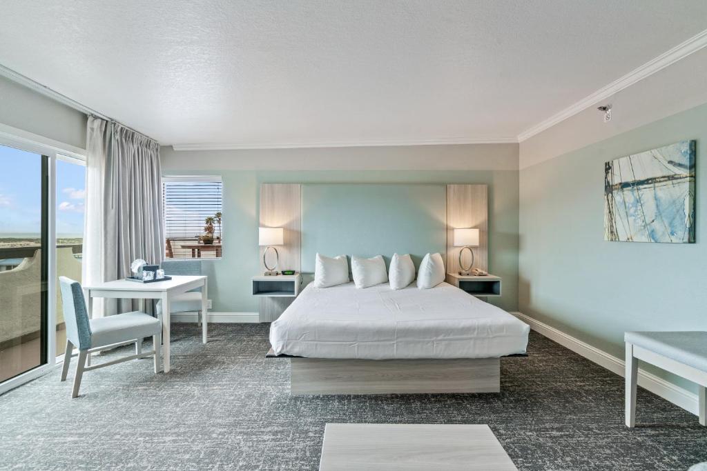 a bedroom with a white bed and a desk and a table sidx sidx at La Serena Inn in Morro Bay