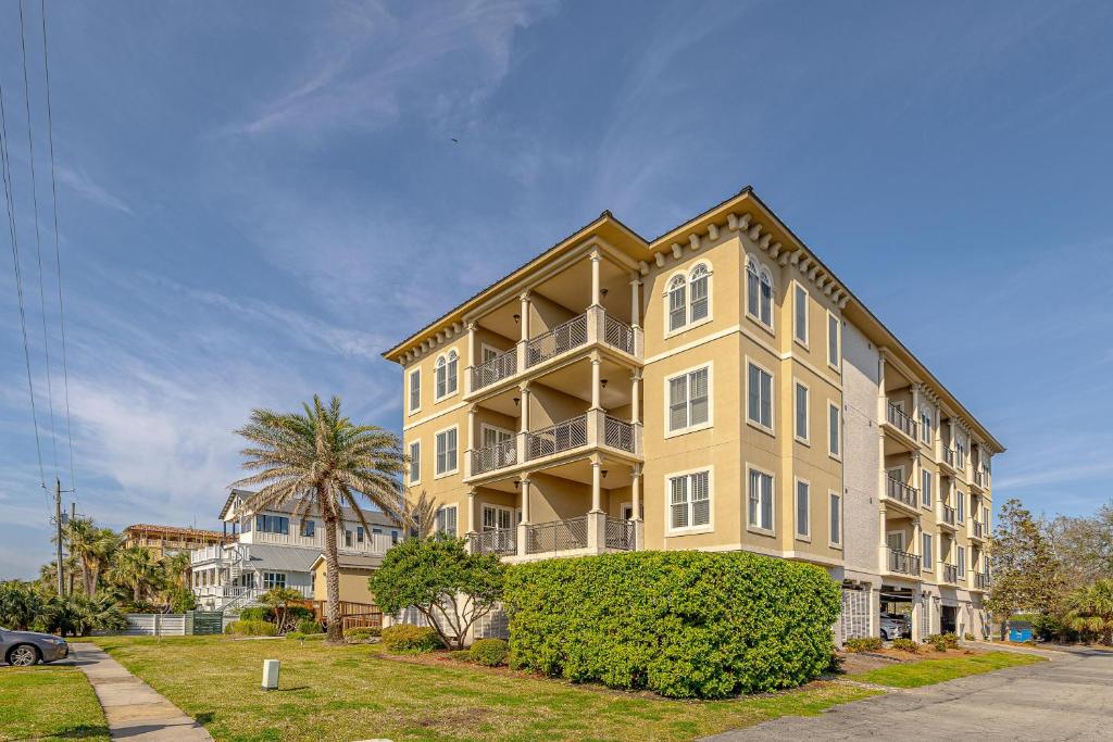 a large yellow apartment building with a palm tree at Sea Gate #105 in Demere Park