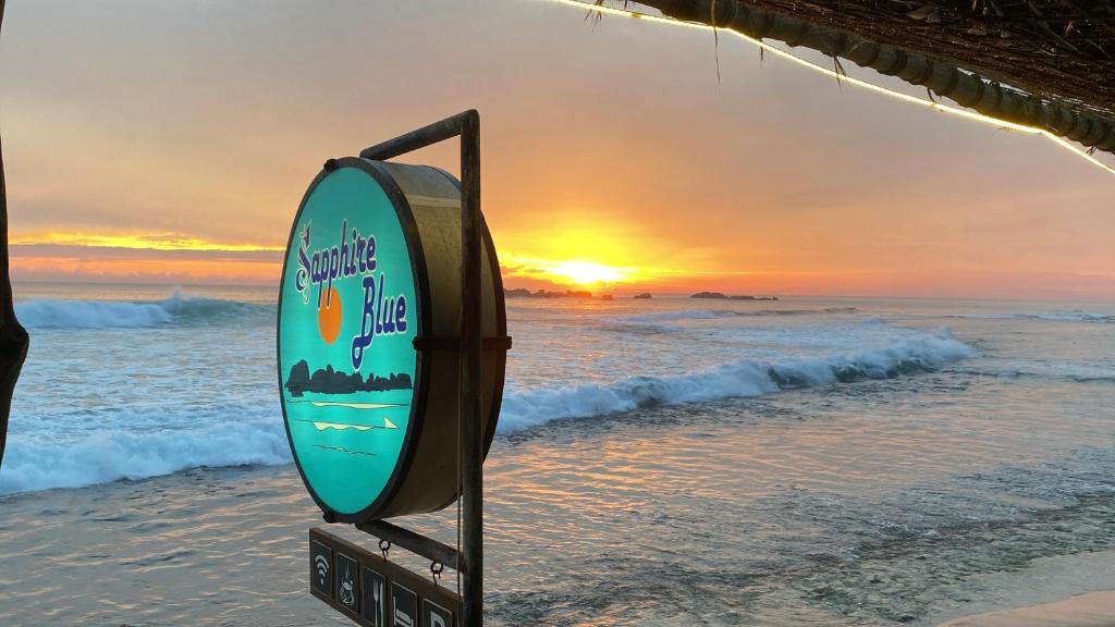 una tabla de surf en la playa con la puesta de sol en el fondo en Sapphire Blue, en Hikkaduwa