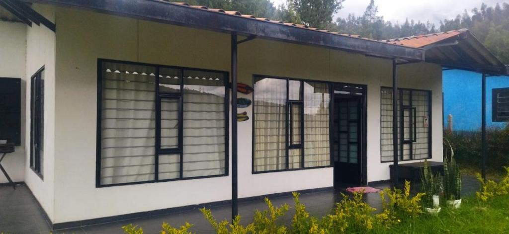 a small house with glass windows and a door at Cabaña La Veranera in Paipa