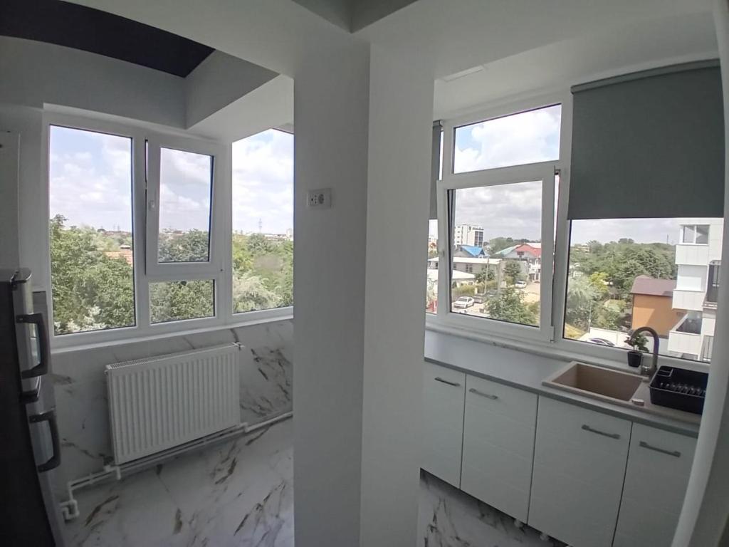 una cucina bianca con tre finestre e un lavandino di Cazare la mare Stefan a Mamaia Nord - Năvodari