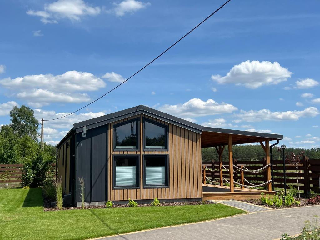 a small cabin with a black roof and windows at Domek Harmony Park in Kondrajec