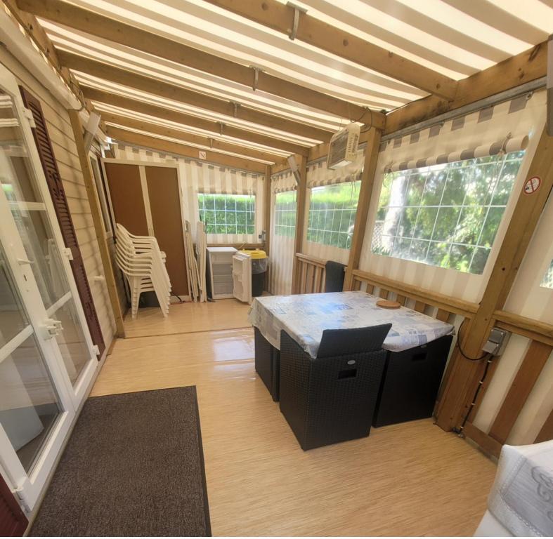 a small house with a kitchen with a table at Mobil Home 3ch CONFORT Camping 4étoiles Les Charmettes 393 Proche FUN ZONE in Les Mathes