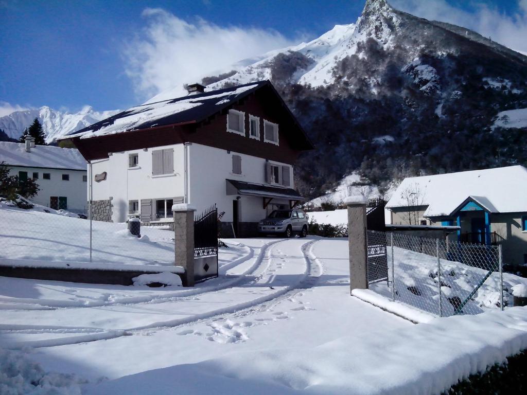 une maison dans la neige avec une montagne en arrière-plan dans l'établissement Chalet les Marmottons, à Cauterets
