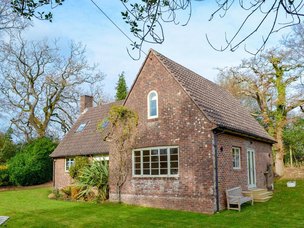 an old brick house with a bench in the yard at Brookside Cottage in Burley