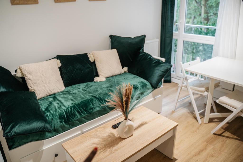 un canapé vert dans un salon avec une table dans l'établissement Escapade à deux ou en télétravail Studio calme avec Parking gratuit, WiFi rapide, proche ligne 14 et Paris centre, à Villejuif