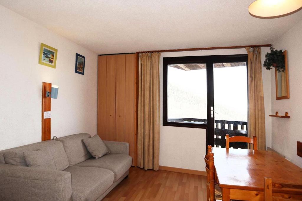 un salon avec un canapé, une table et une fenêtre dans l'établissement Résidence Le Cairn - studio 10ème étage le cairn MAE-6581, aux Orres