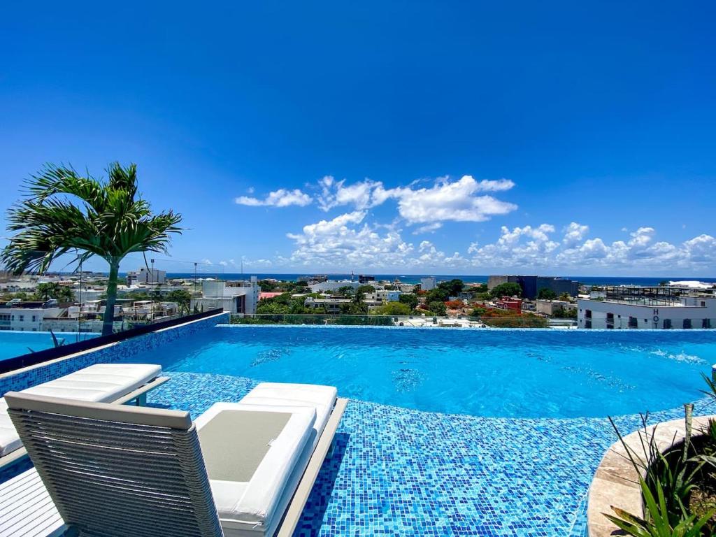 a swimming pool with chairs and a view of the ocean at Downtown Playa Studio with Rooftop Pool Steps to Everything in Playa del Carmen