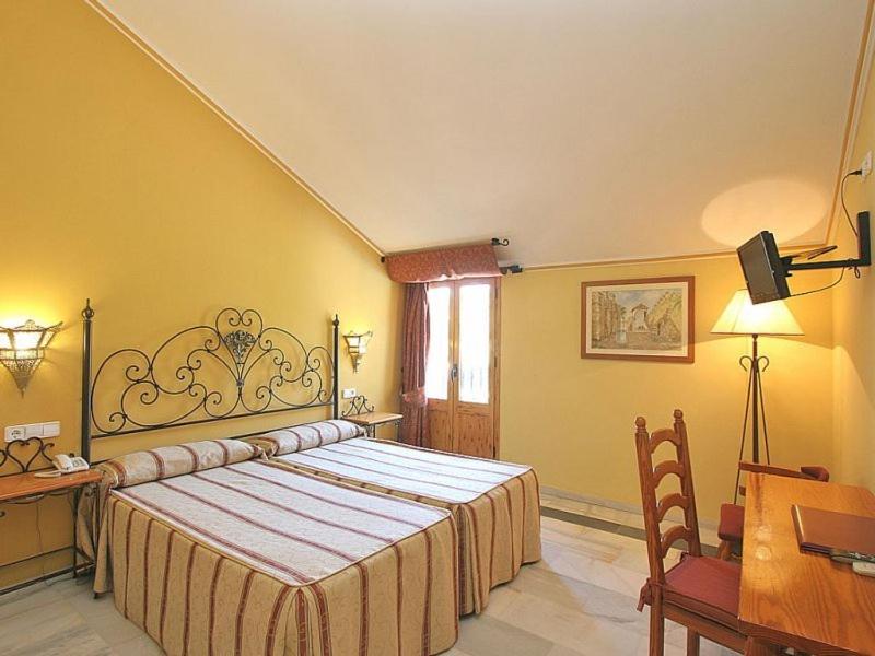 a bedroom with a large bed and a table and a desk at Hotel El Paso in Vejer de la Frontera