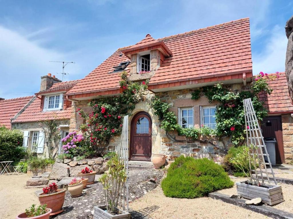 une maison en pierre avec un toit rouge et des fleurs dans l'établissement Résidence D06-tregastel - Découvrez Torr Penn nichée dans les rochers roses MAE-1741, à Trégastel
