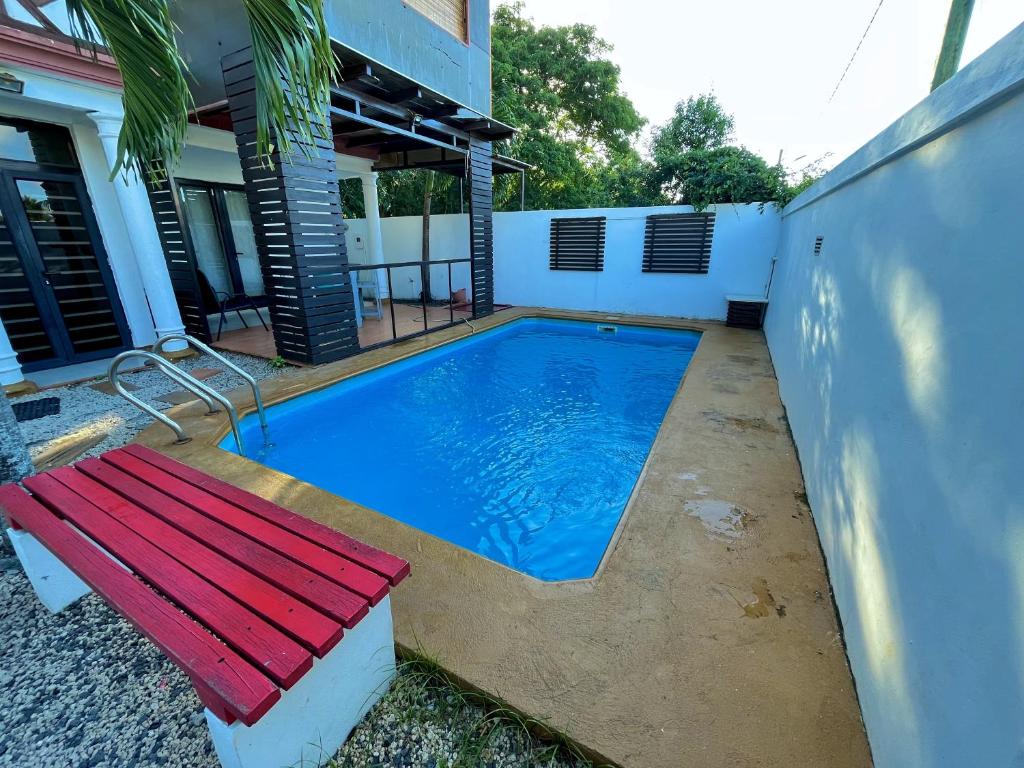 a swimming pool with a red bench next to a house at Sandy Lane Escape - Grand Baie in Grand Baie