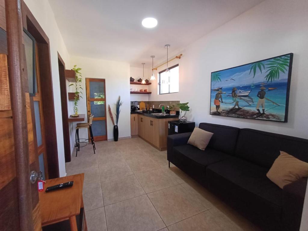 a living room with a black couch and a kitchen at Casa Praia - Recanto Tucuns Beira-Mar in Búzios