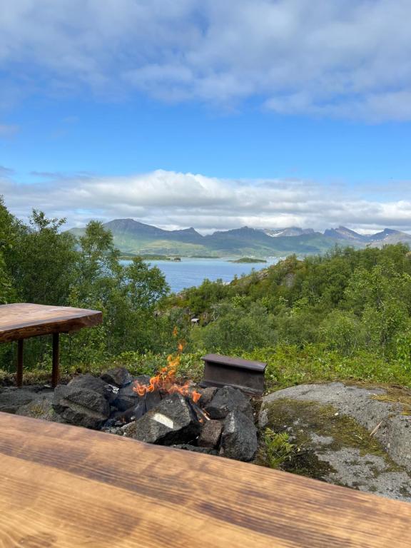a fire pit with a picnic table and a lake at Practical and cozy cottage in idyllic Senja in Senja
