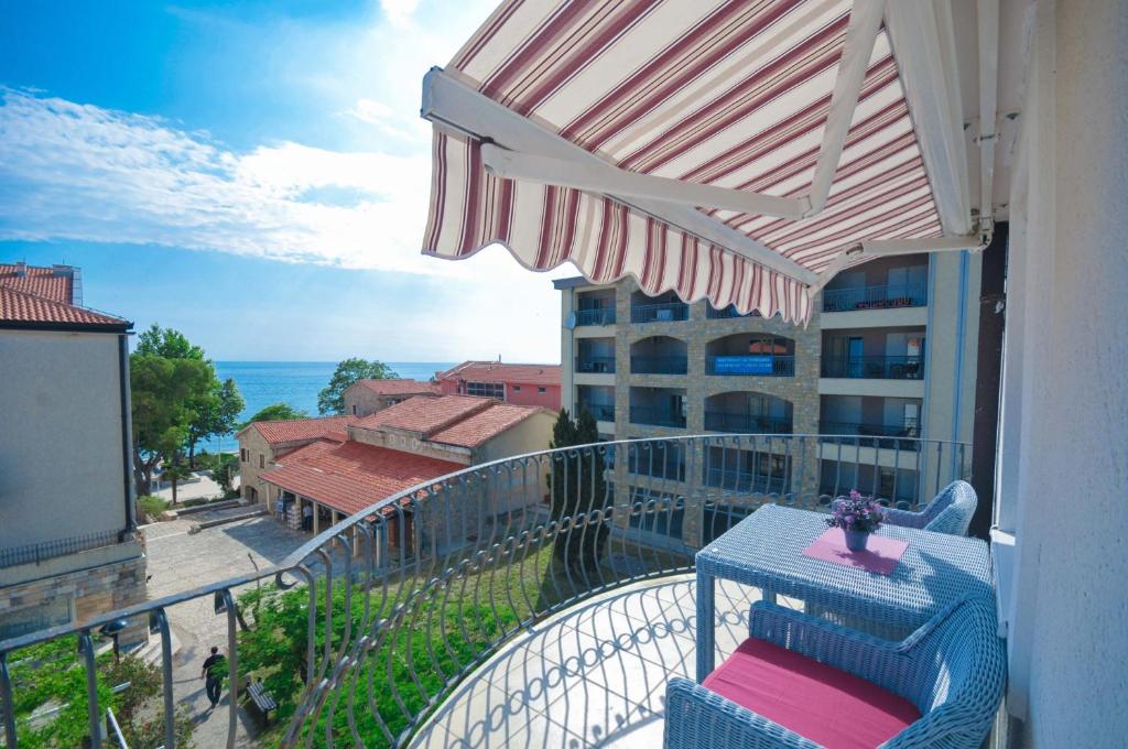 - Balcón con silla y sombrilla en Seaside Apartments Petrovac, en Petrovac na Moru