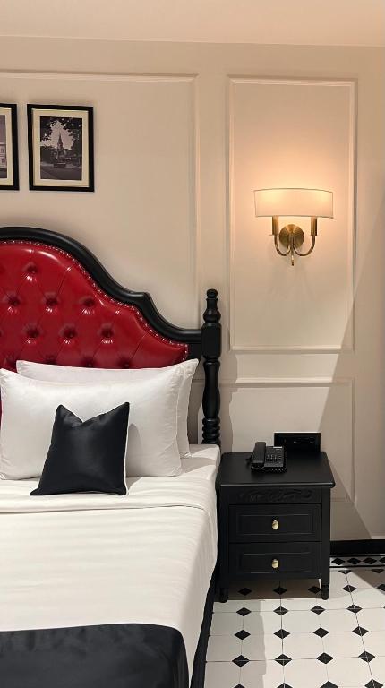a bedroom with a bed with a red headboard and a table at Hotel Bengal Kutir in Rāiganj