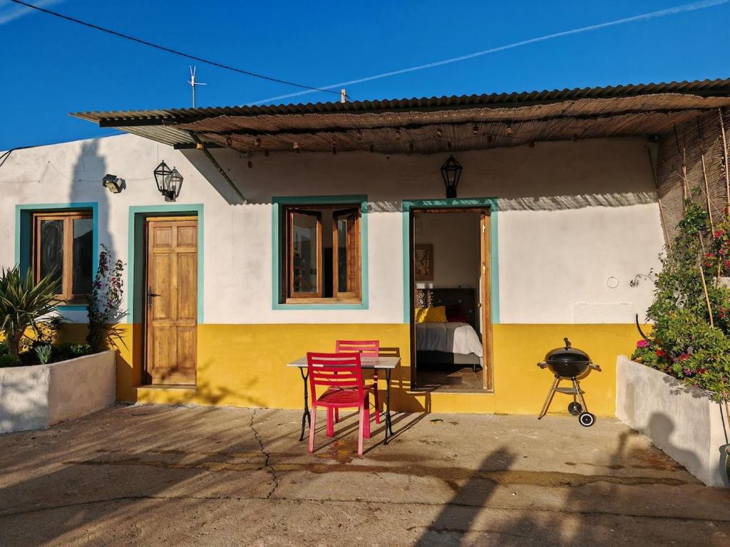 une maison jaune et blanche avec des chaises rouges et une table dans l'établissement Los Nopalitos 2 - Estudio chulísimo súper equipado a 3,5km de Carboneras, à El Llano de Don Antonio