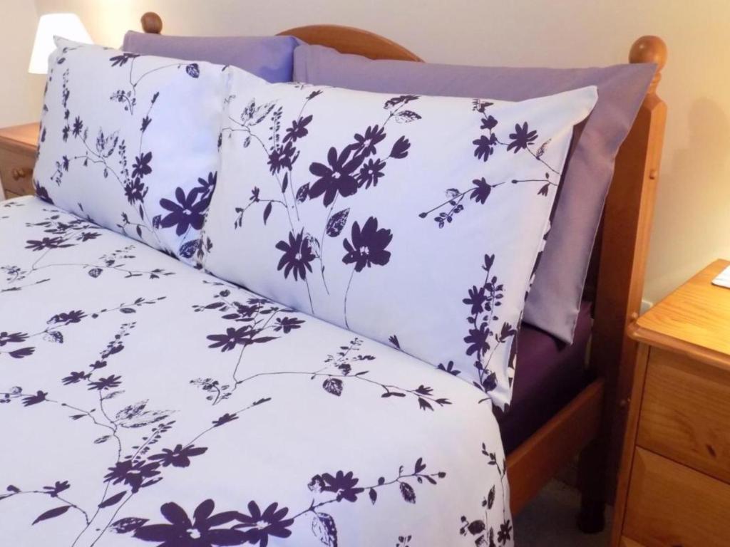 a bed with a white bedspread with blue flowers at Bosta 12 Knock in Stornoway