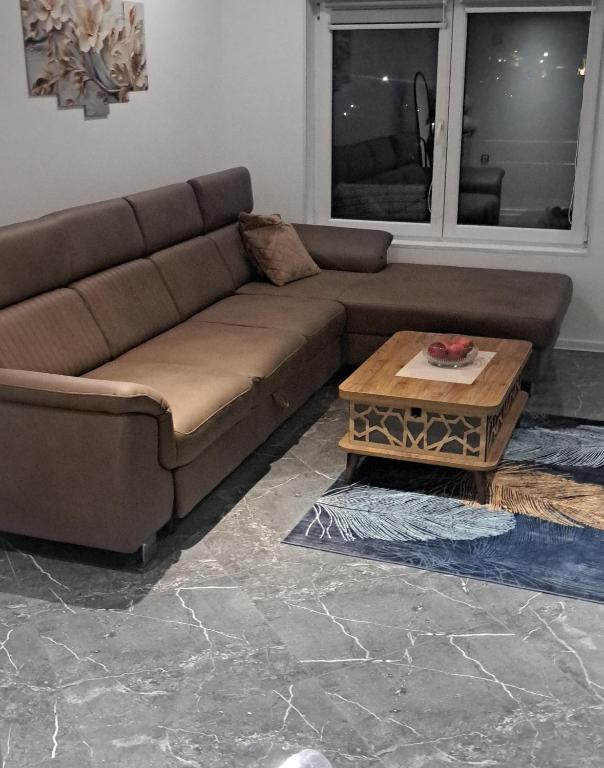 a brown couch in a living room with a table at Apartman hukanovic in Bosanska Krupa