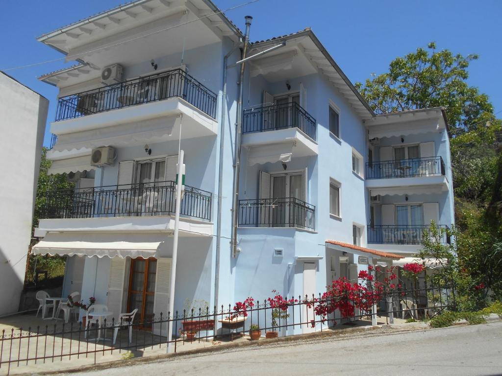 a white building with balconies on a street at Villa Hermione in Agia Paraskevi