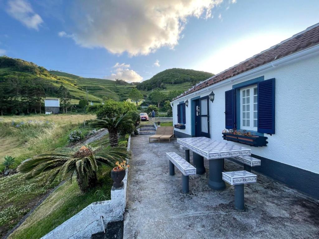 a picnic table outside of a house with mountains in the background at Quinta do Monte Santo in Vila do Porto