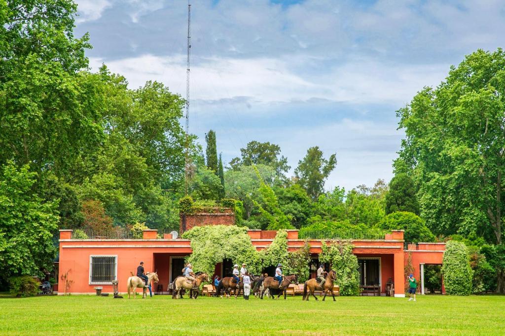 a group of people riding horses in front of a building at Estancia La Bandada in San Miguel del Monte