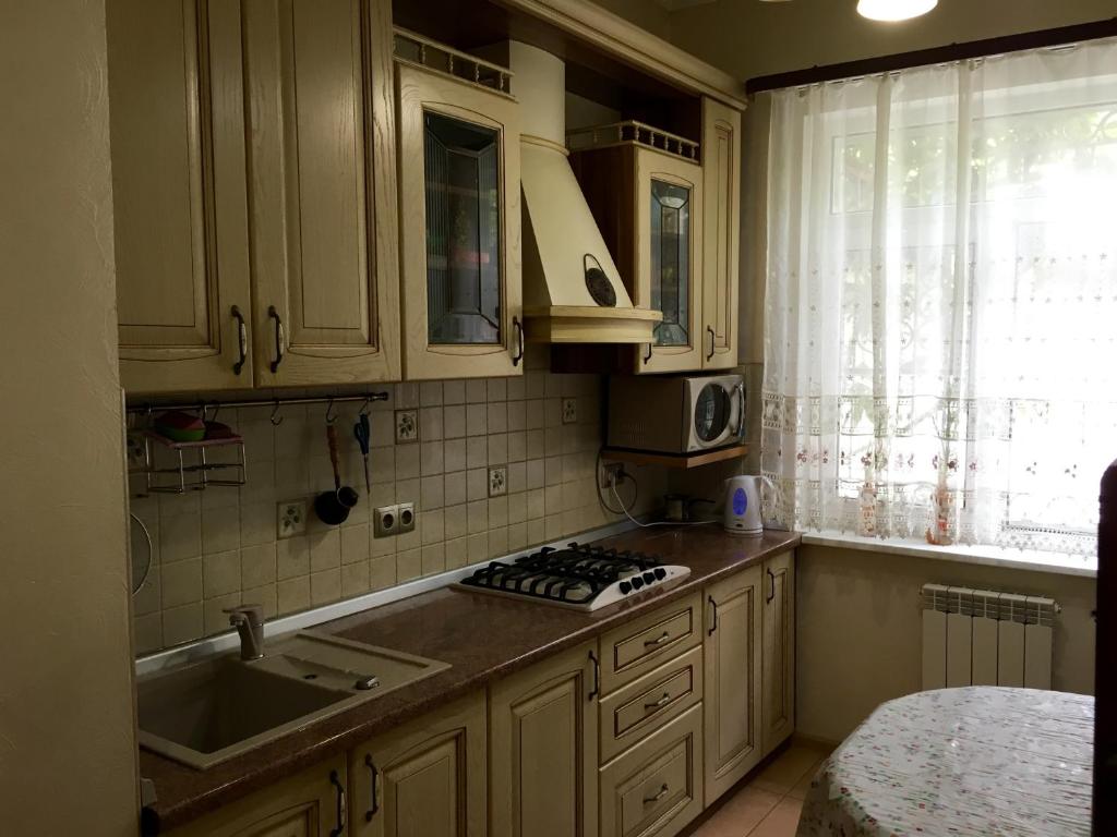 cocina con armarios blancos, fregadero y ventana en Guest House Aleksina, en Lazarevskoye