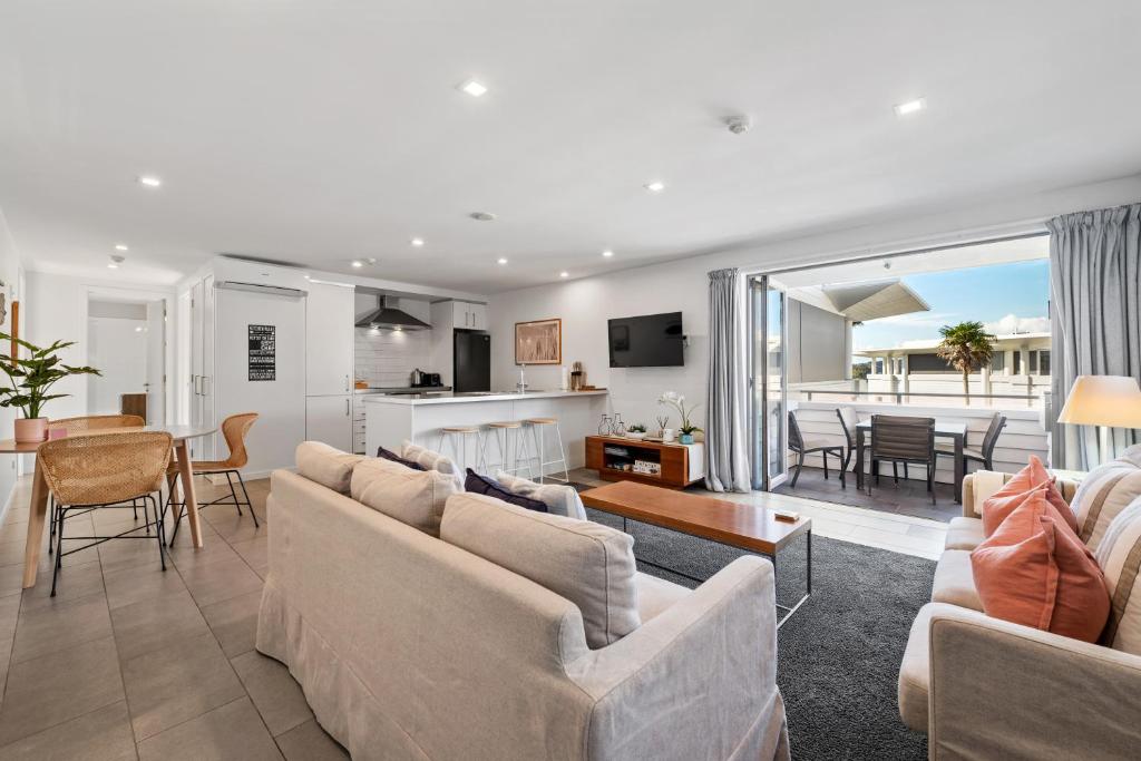 a living room with couches and a dining room and a kitchen at Paihia Waterfront Apartment 2 Bedroom with Pool in Paihia