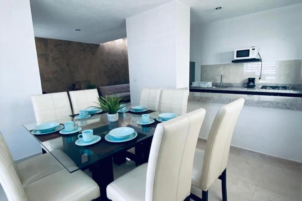 a dining room with a table and white chairs at Casa venue in Mérida