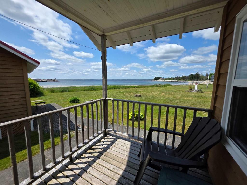 a porch with a chair and a view of the ocean at Hunts Point Beach Cottages - Cottage #2 in Summerville Centre