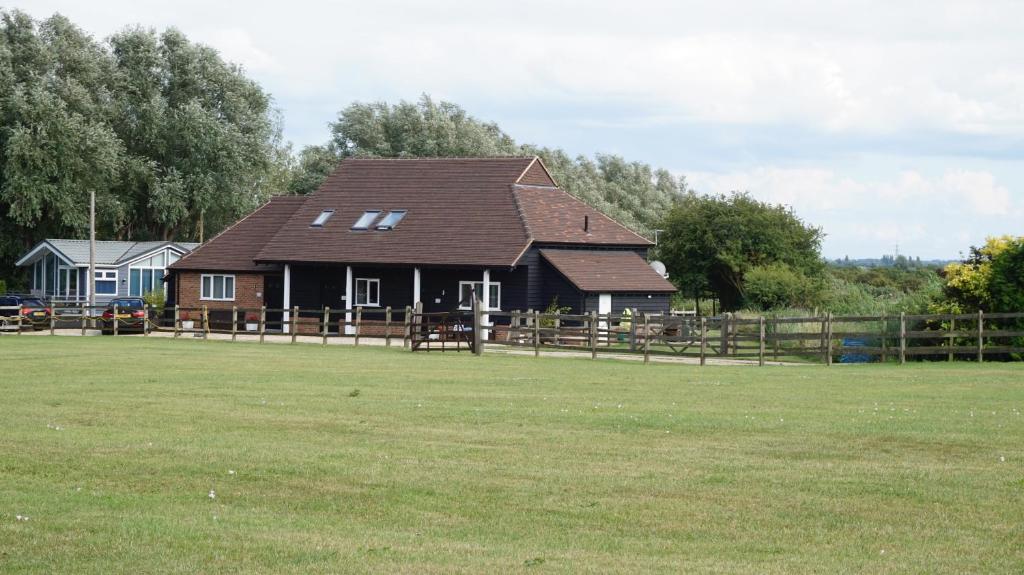 a brown house with a brown roof in a field at Footpath Cottages 