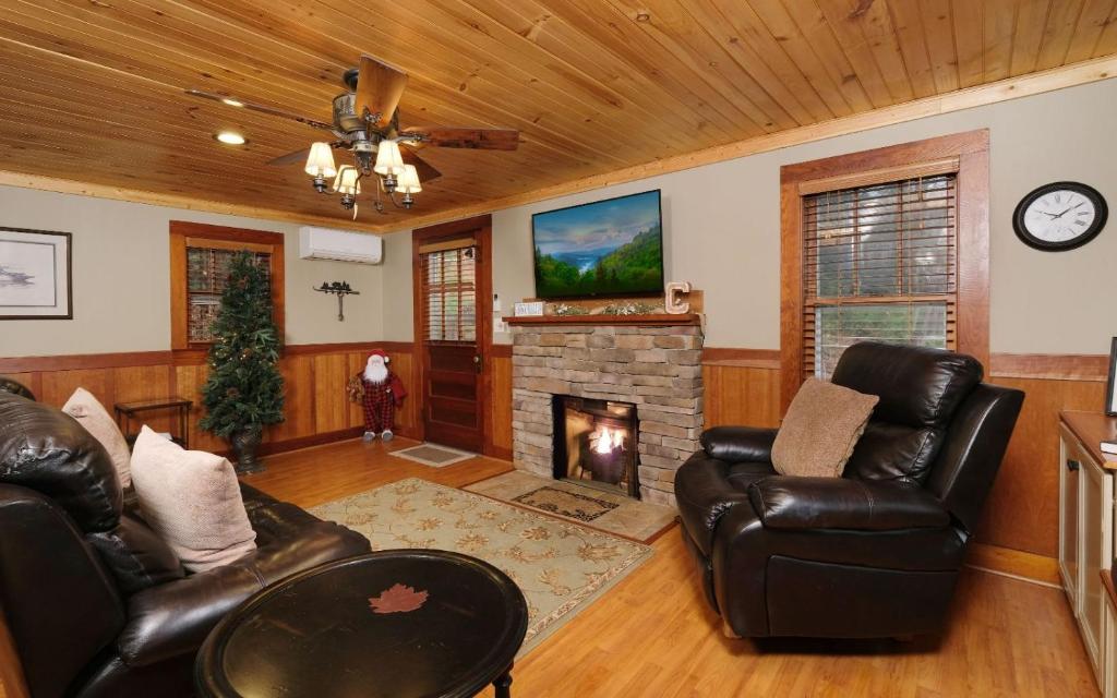 een woonkamer met lederen meubels en een open haard bij Karens Cozy Cottage in Gatlinburg
