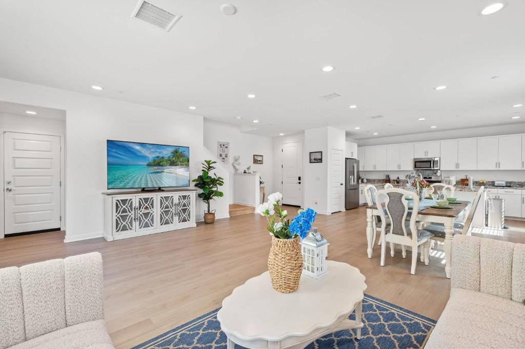 a white living room with a table and a kitchen at Spacious 5BR Getaway w Game Room & Modern Comfort in Fontana