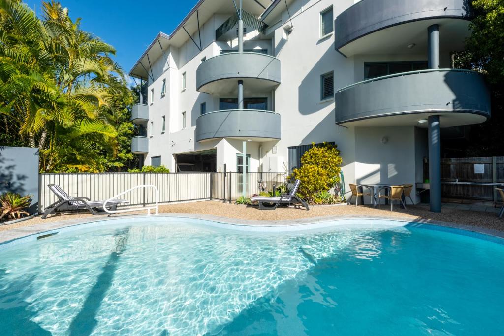 a swimming pool in front of a building at Noosa River Sandy Shores in Noosaville