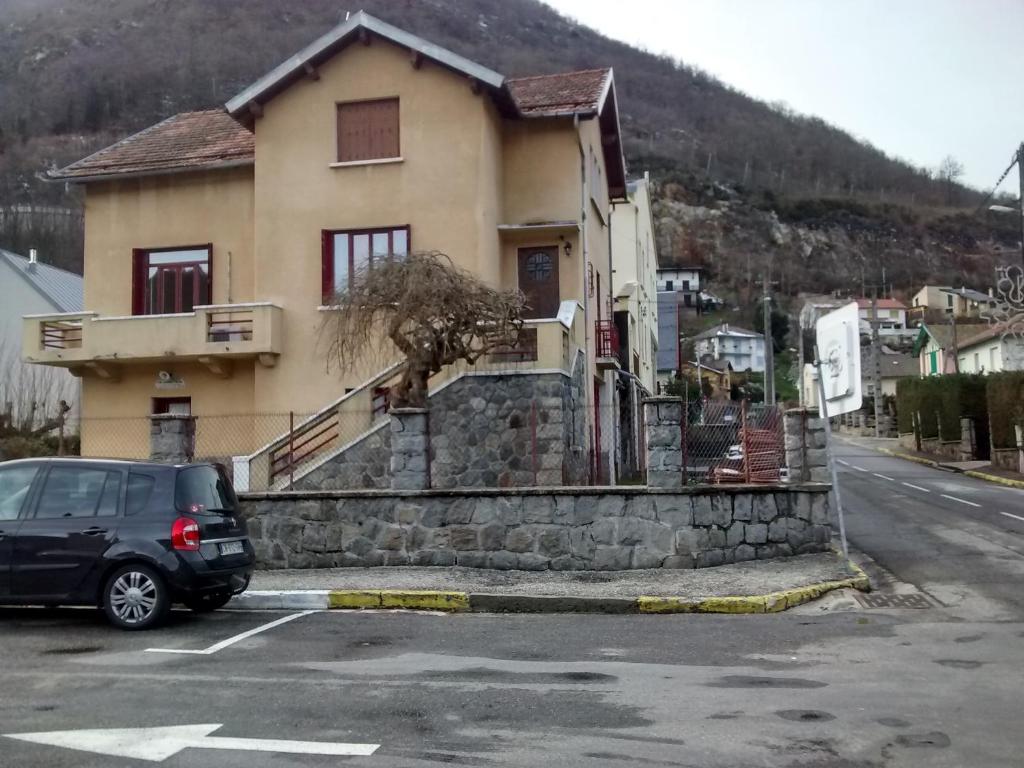une voiture garée dans un parking en face d'une maison dans l'établissement Villa Marguerite, à Ax-les-Thermes