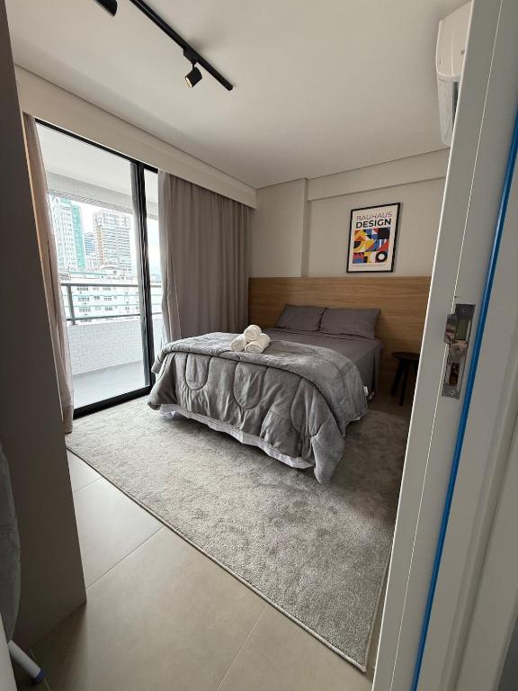 a bedroom with a bed and a large window at Stay Santos - Moderno e Bem Localizado in Santos