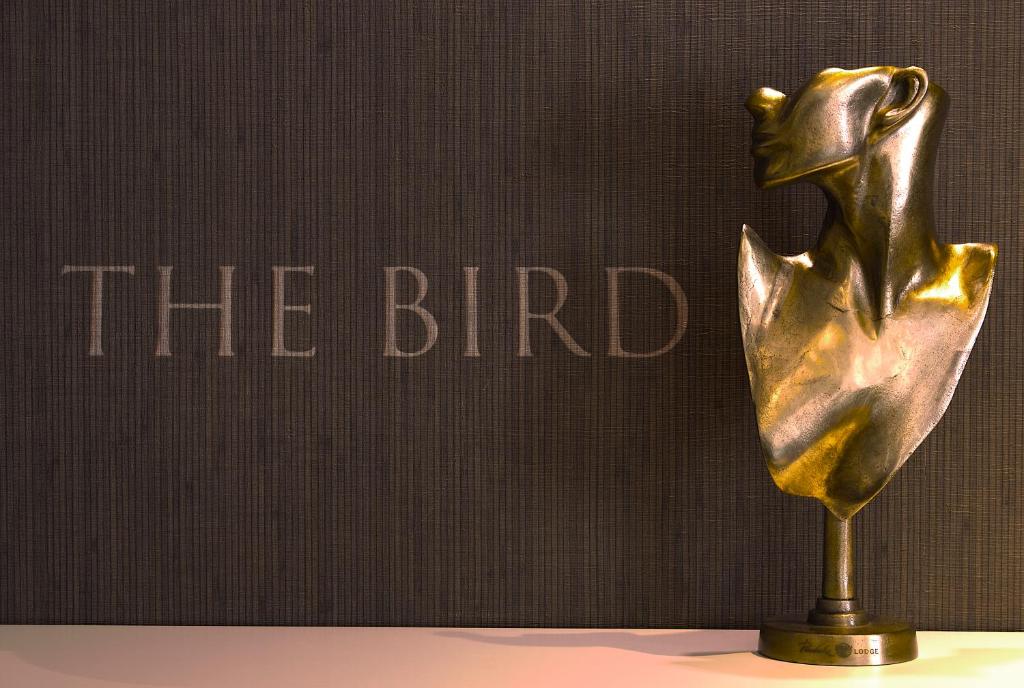 une statue en bronze d'une femme devant un livre dans l'établissement Hotel The Bird, à Amsterdam