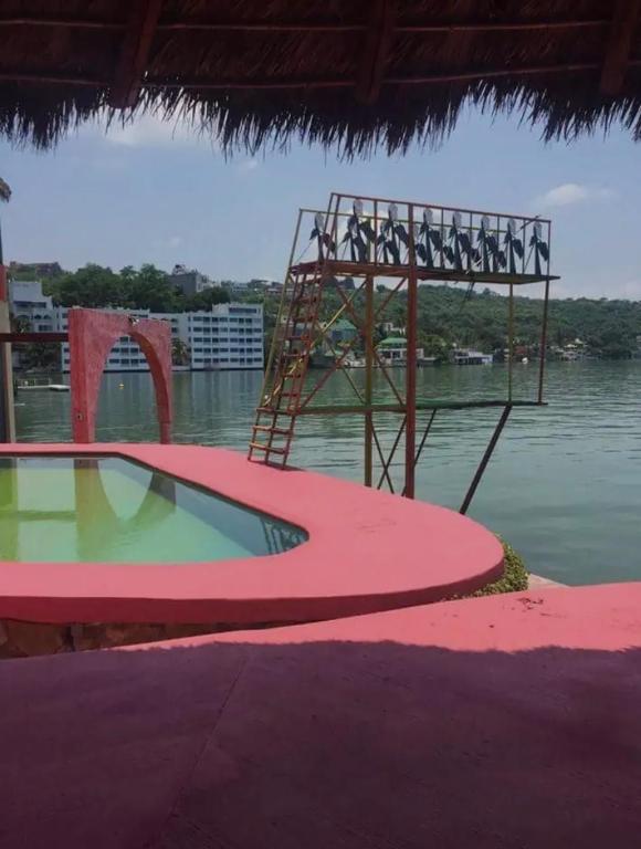 a swimming pool with a metal structure next to the water at Casa Mandarina in Tequesquitengo