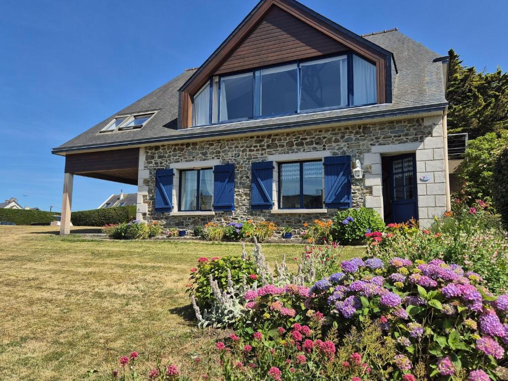 une maison avec des fenêtres bleues et des fleurs dans la cour dans l'établissement Apartment in Pordic near Sandy Beach, à Pordic
