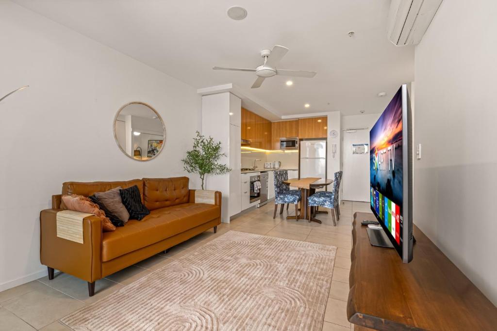 Una sala de estar con un sofá y un televisor de pantalla plana. en Stylish Apartment with Rooftop BBQ & Spa Access, en Brisbane