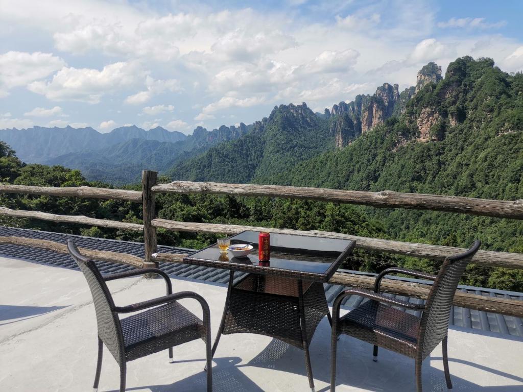 einen Tisch und Stühle auf einem Balkon mit Bergblick in der Unterkunft PeakMist Retreat Inside ZhangJiaJie Forest Park in Zhangjiajie