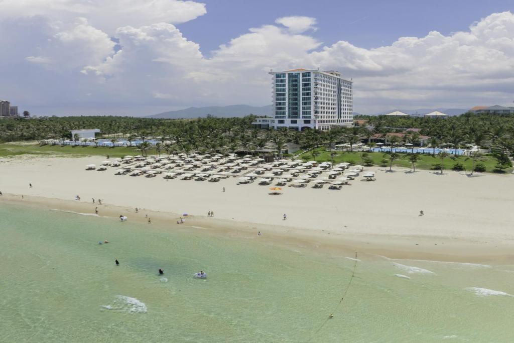 a beach with a lot of chairs and a building at Swandor Cam Ranh Resort-Ultra All Inclusive in Cam Ranh
