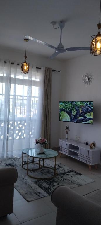 a living room with a table and a tv on the wall at The Pearl in Mombasa