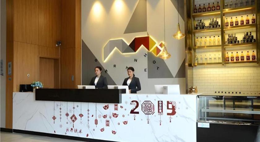 Dos mujeres sentadas en un mostrador en un restaurante en Borrman Hotel Zhanjiang Xuwen Port Terminal, en Xuwen