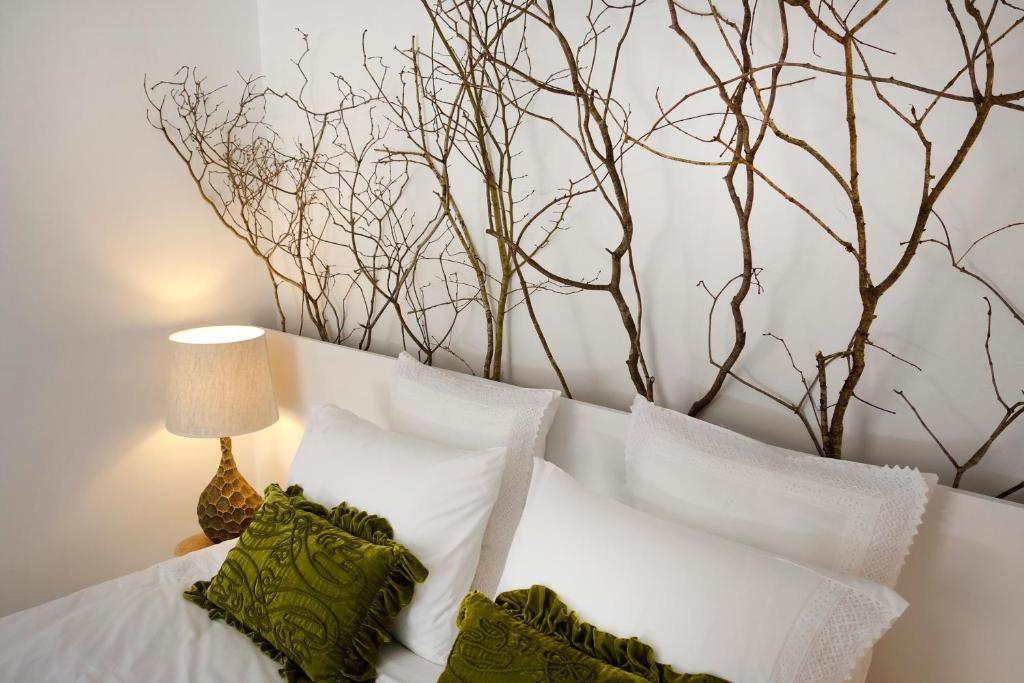 a bed with white pillows and a tree on the wall at Sparrow Sintra Nest in Sintra