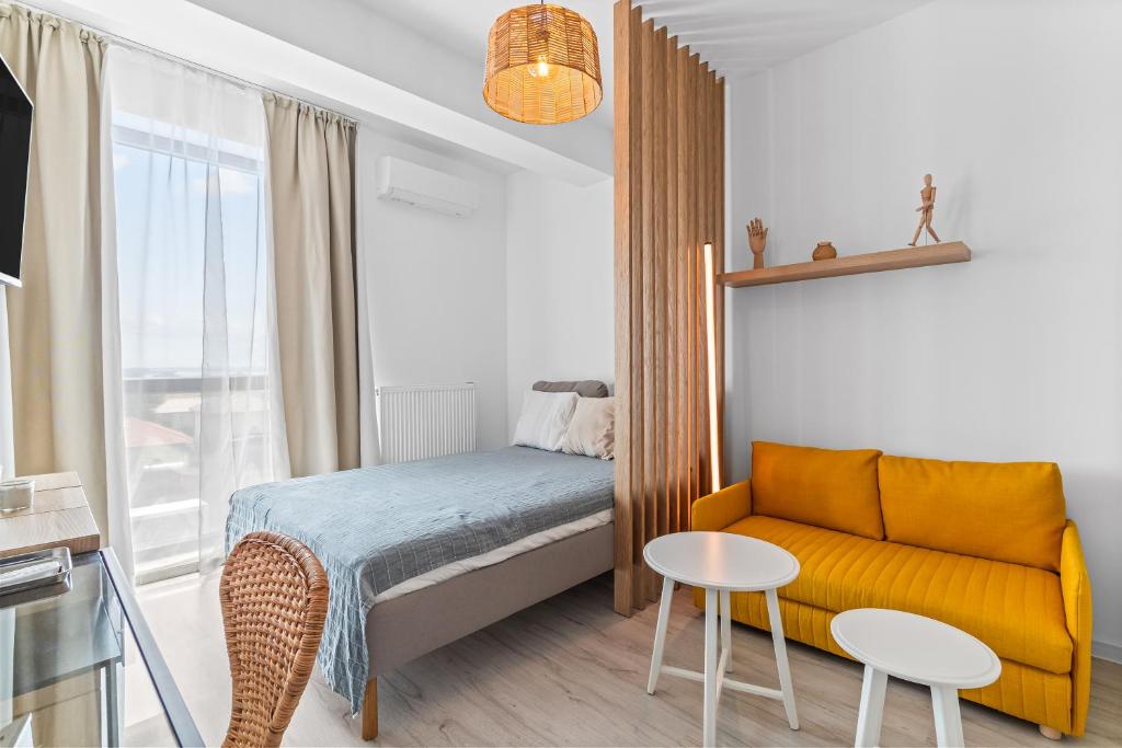 a small bedroom with a bed and a yellow couch at Boemia Studio in Mamaia Nord