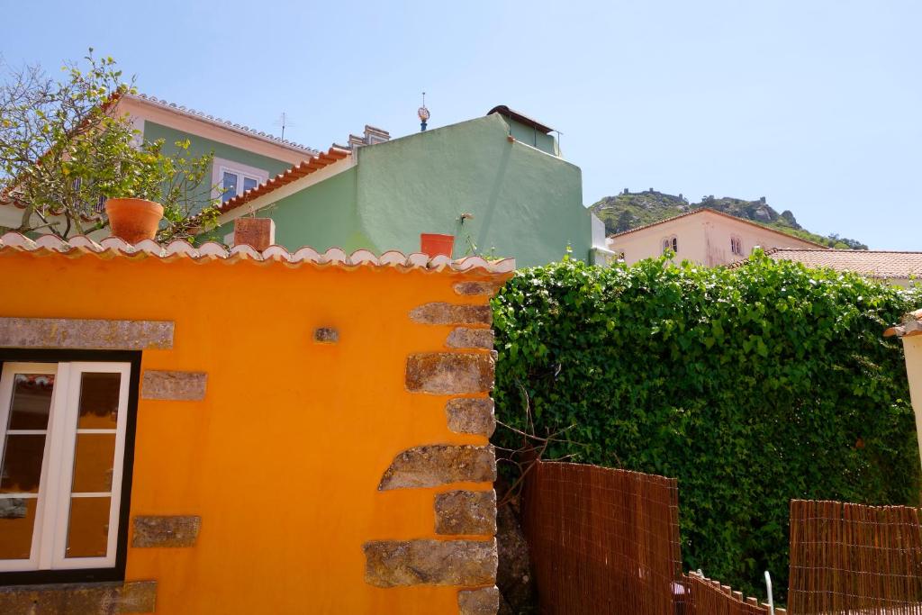 an orange building with a fence and a hedge at Sparrow Sintra Nest in Sintra