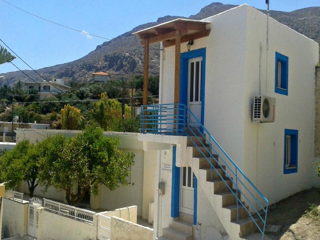 une maison blanche avec des portes et des escaliers bleus. dans l'établissement Tania village Zakros maisonette, à Zakros