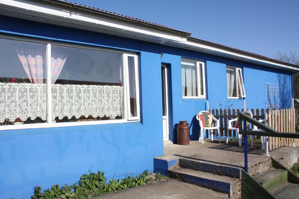 a blue house with a window and a chair at CJA Guesthouse in Laugar