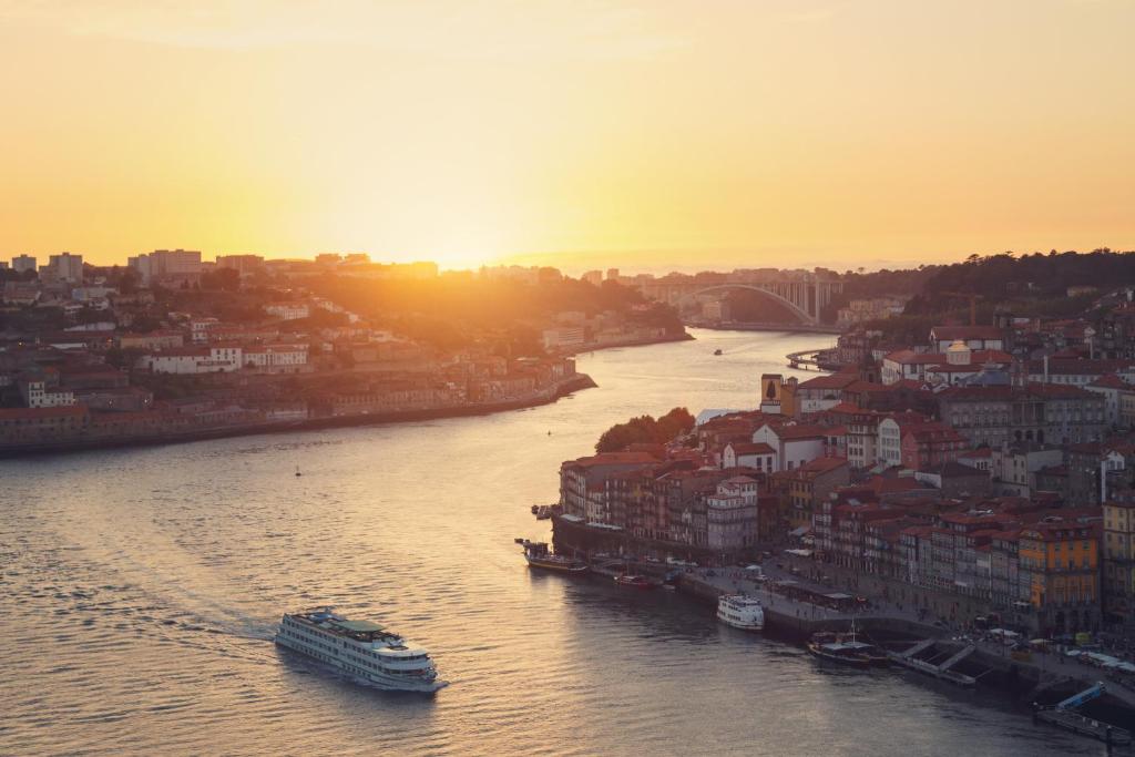 a river with a city and a boat in the water at Apartamento LM Ribeira in Porto